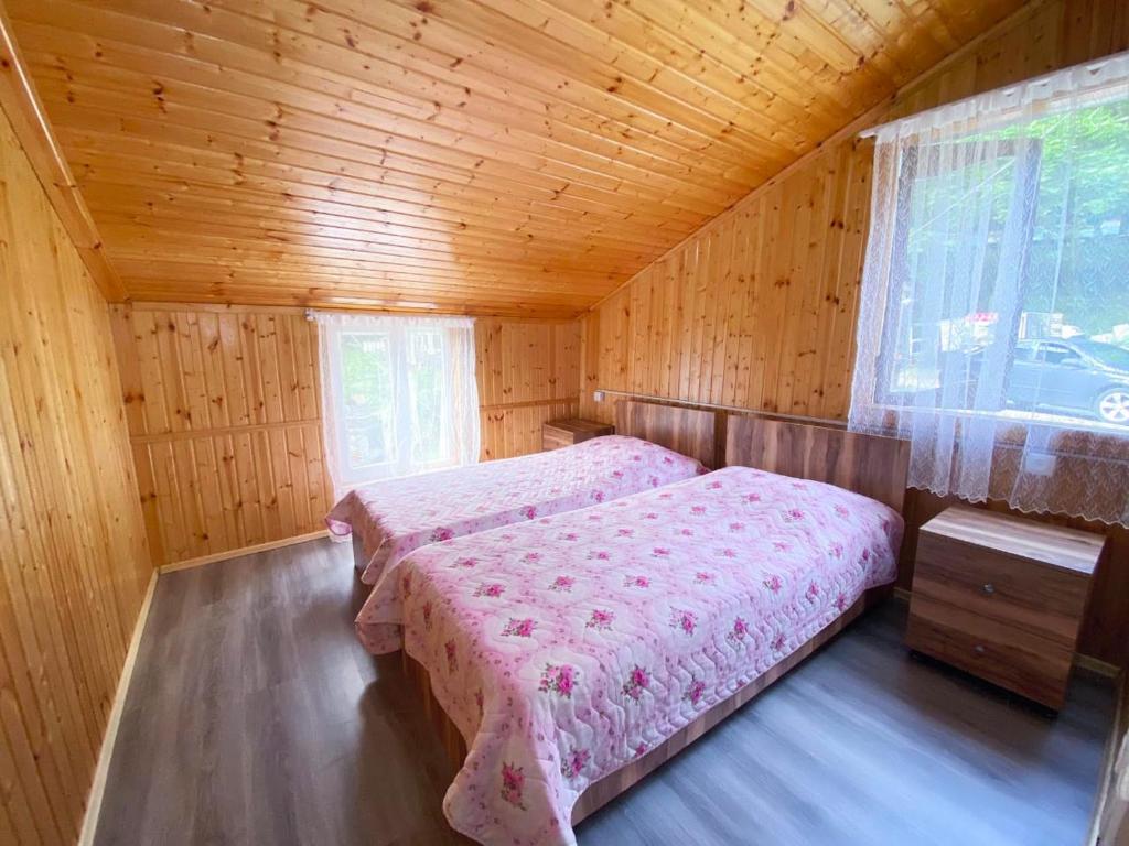 a bedroom with two beds in a wooden cabin at MTIRALA HOTEL ZIPO in Ch'ak'vist'avi