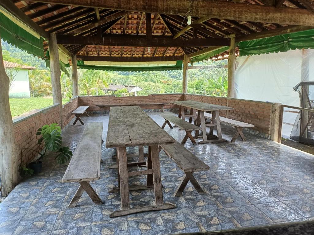 um grupo de mesas de piquenique sob um pavilhão em Sítio Vale dos Reis em Resende