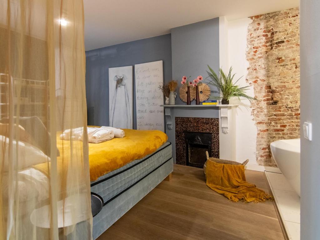 Schlafzimmer mit einem Bett, einem Kamin und einer Badewanne in der Unterkunft Georgia's Bathhouse in Breda