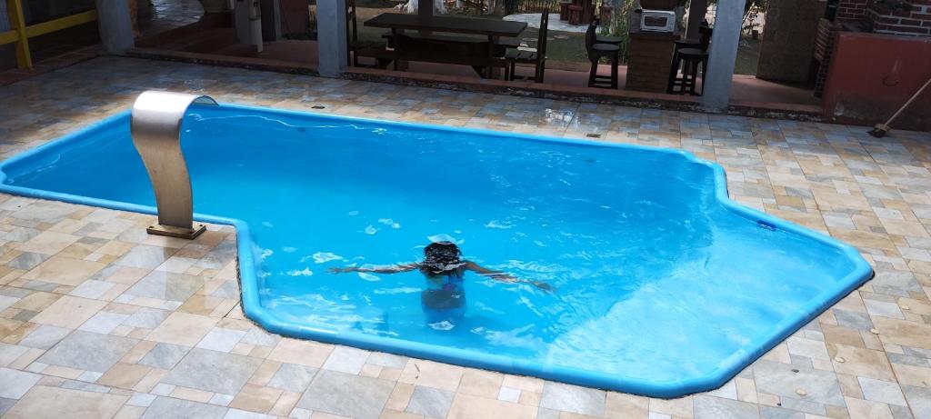 a person in a swimming pool in a blue pool at Fazenda Riachão in Pojuca