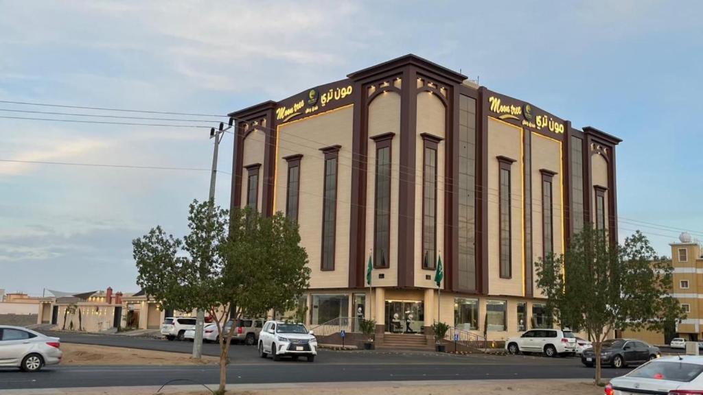 ein großes Gebäude mit Autos auf einem Parkplatz in der Unterkunft فندق وفلل مون تري in Najran