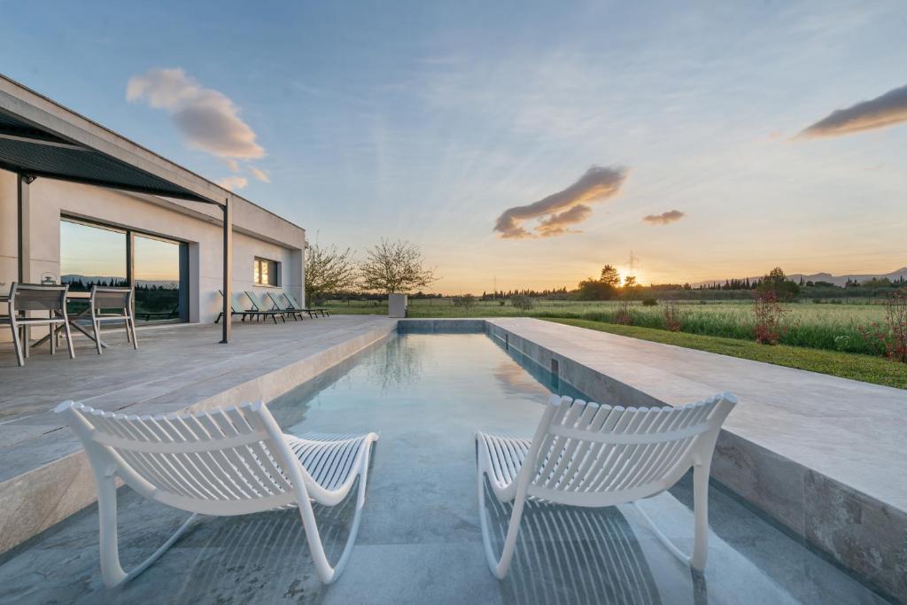 two white chairs sitting next to a swimming pool at Casa Blanca in Sencelles