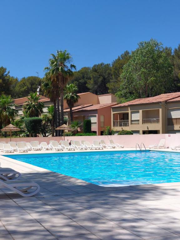 une piscine avec des chaises longues et un complexe hôtelier dans l'établissement T2 avec piscine et accès privé à la mer, à Sanary-sur-Mer