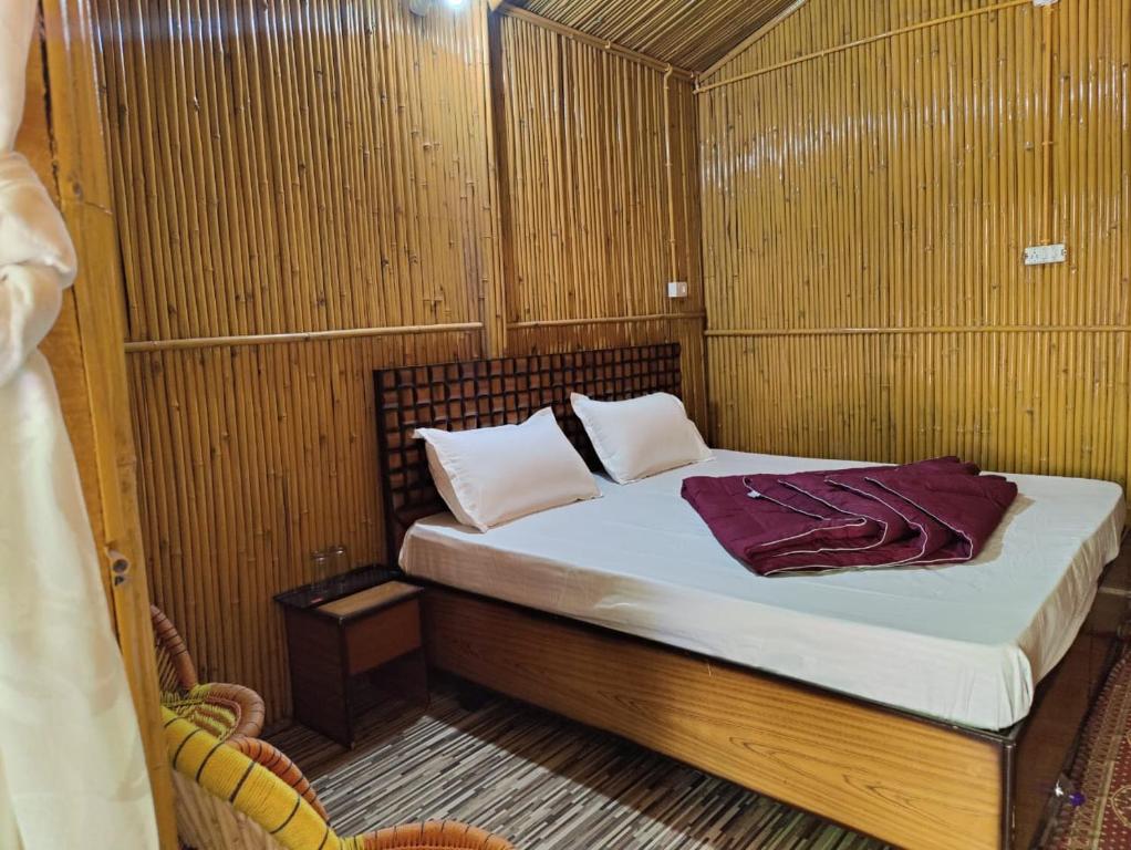 ein kleines Bett in einem Zimmer mit Holzwänden in der Unterkunft Moupiya Resort and Restaurant in Dāngchura