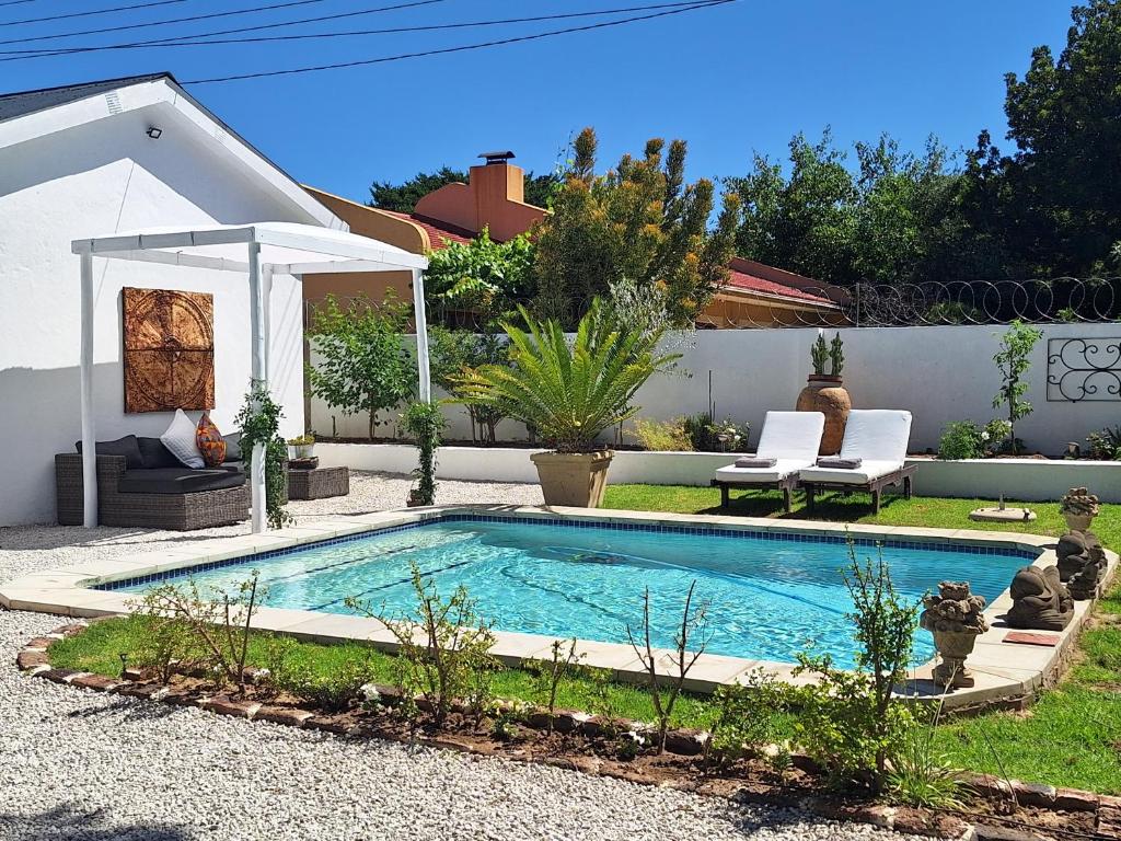 uma pequena piscina num quintal com duas cadeiras em Acacia Home em Graaff-Reinet