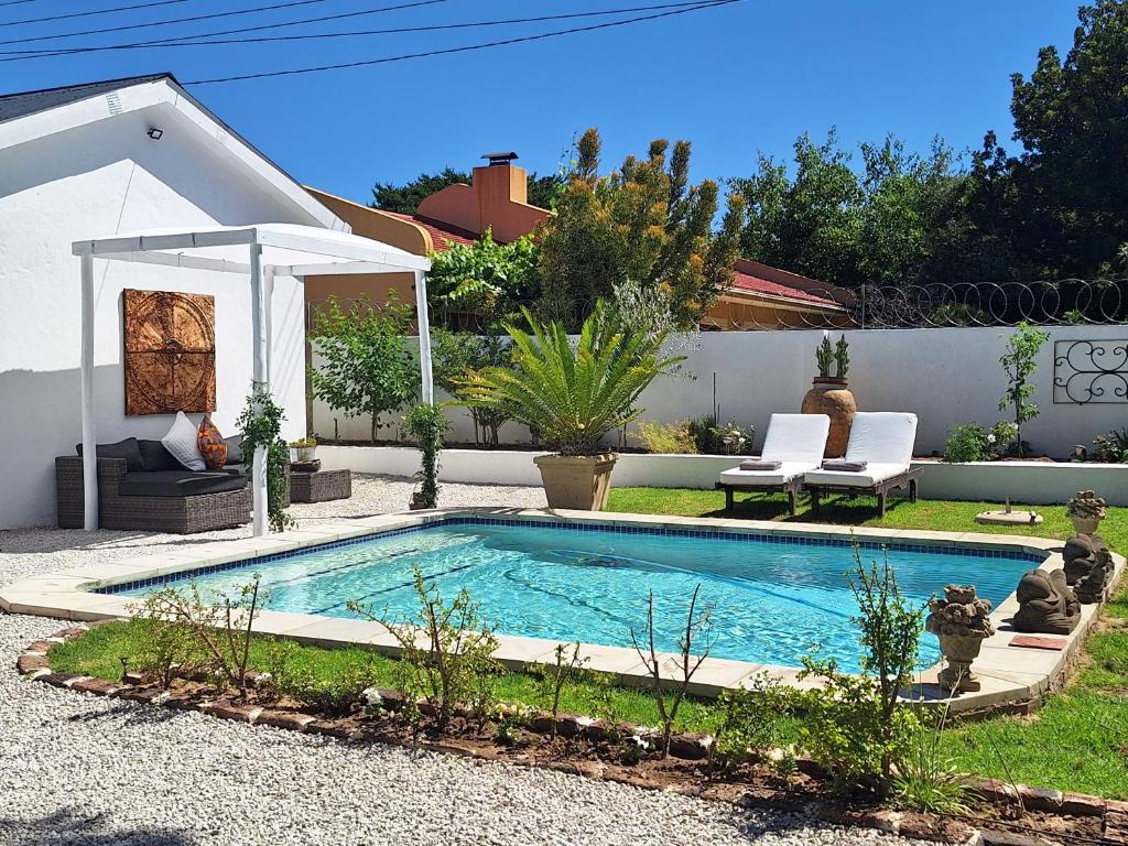 a small swimming pool in a yard with two chairs at Acacia Home in Graaff-Reinet