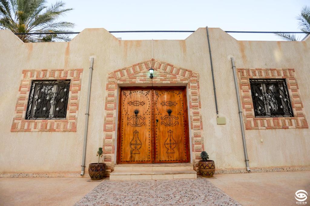 a building with a wooden door with two windows at Dar Barka in Kebili