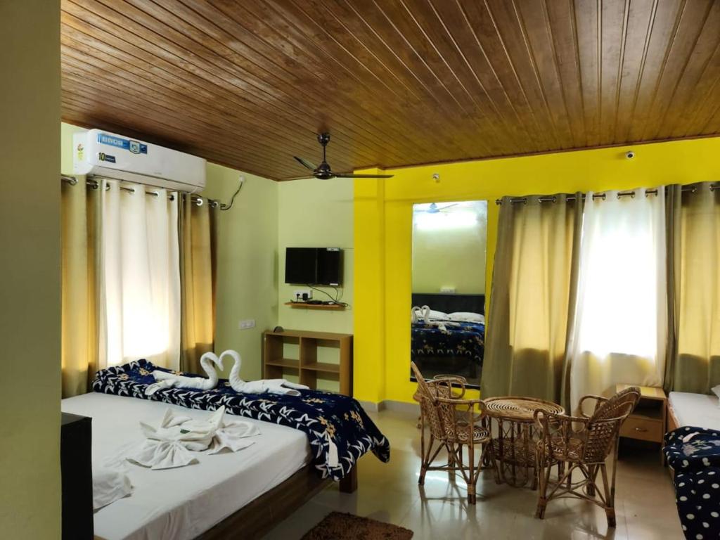 1 dormitorio con 2 camas, mesa y sillas en Bonobithikaloy Resort & Restaurant, en Chālsa Mahābāri