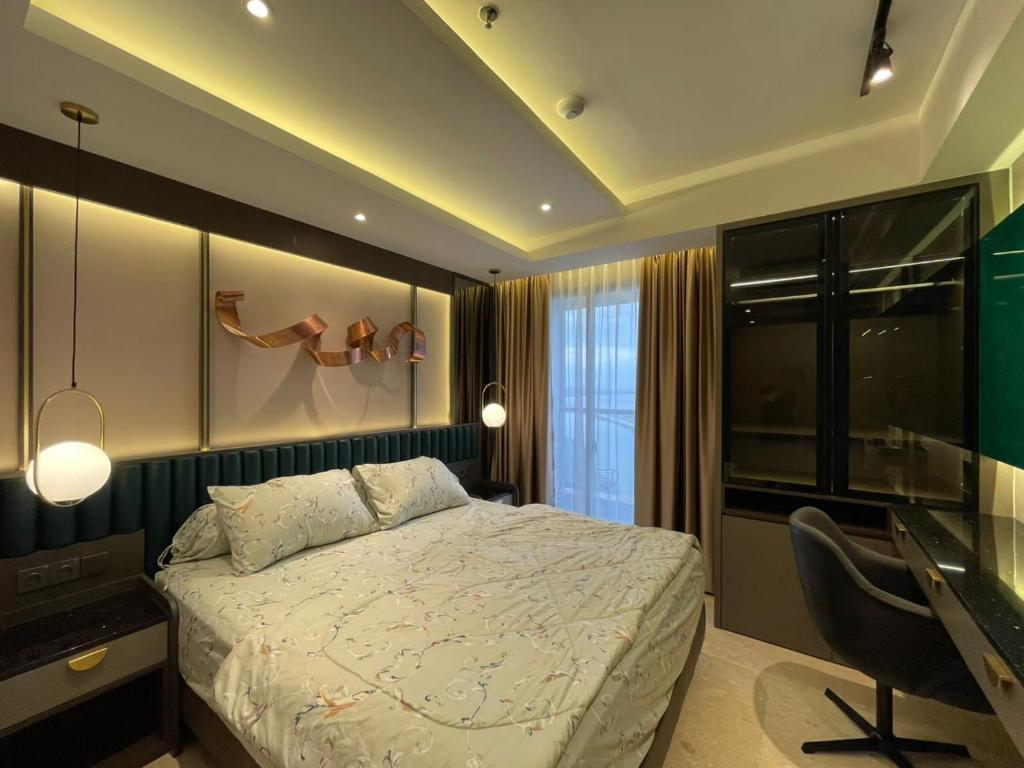 Gold Coast Apartemen PIK by Dluxx في جاكرتا: غرفة نوم بسرير ومكتب وكرسي