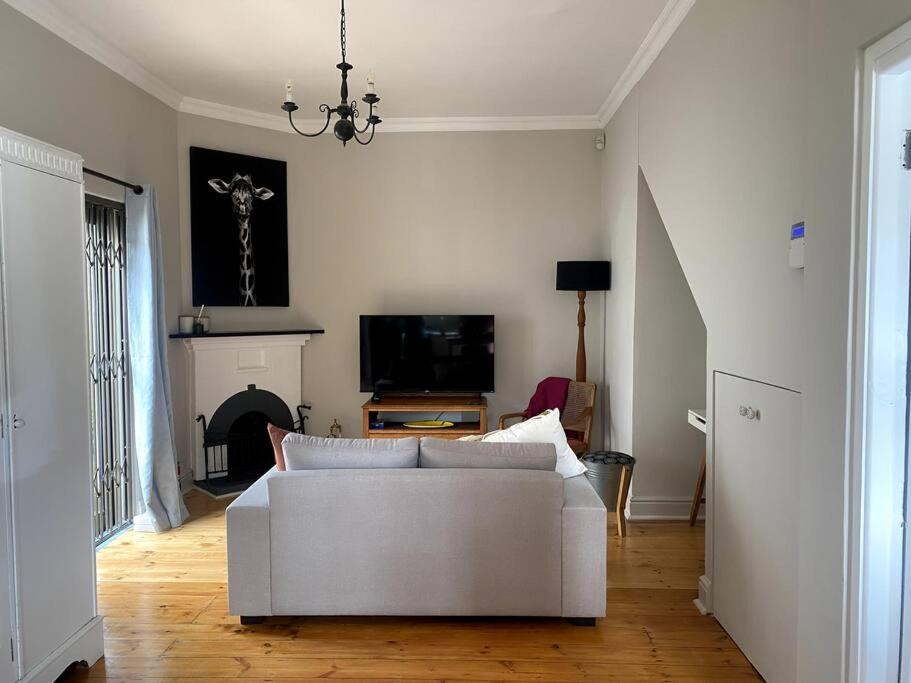 Milner Cottage: Digital Nomad Oasis في كيب تاون: غرفة معيشة مع أريكة بيضاء ومدفأة