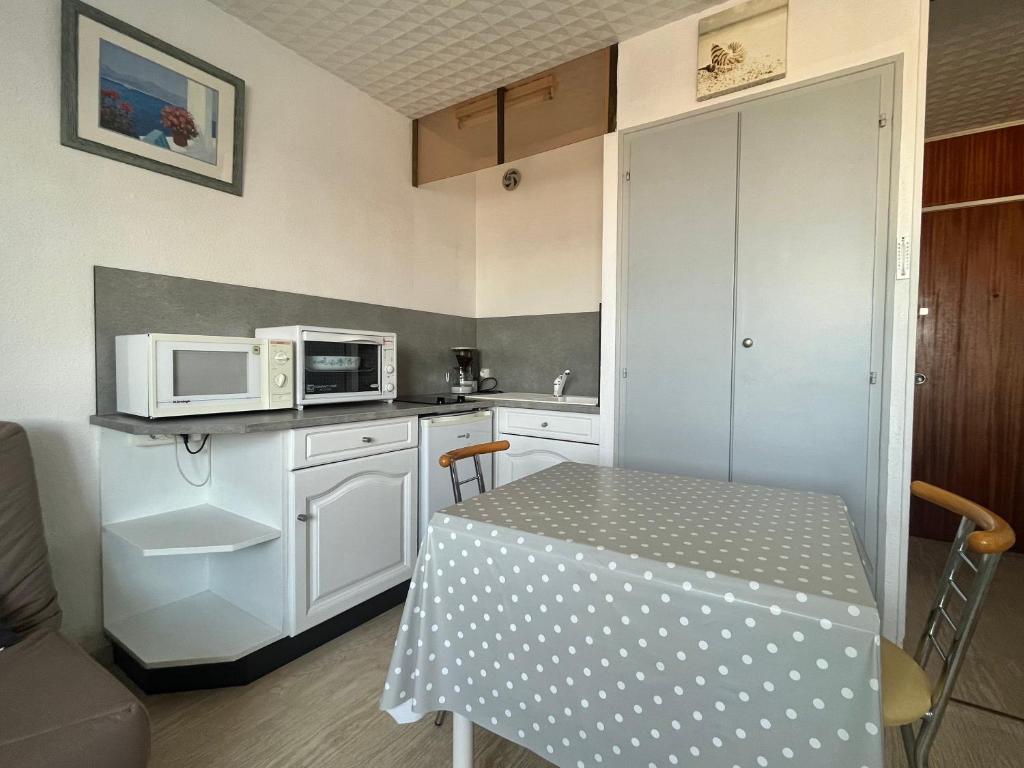 a small kitchen with a table and microwave at Studio - Arc En Ciel 2 - 27 allée des Pinons - 3-1 in Saint-Jean-de-Monts