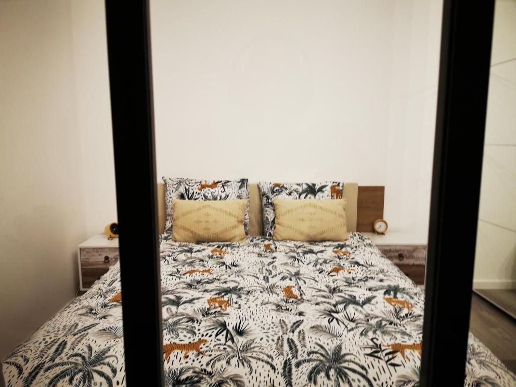 1 dormitorio con 1 cama con colcha y palmeras en AtHome - Appart-hotel with private parking en Esch-sur-Alzette