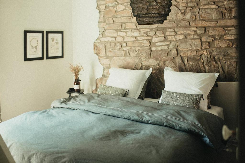 - une chambre avec un grand lit et un mur en pierre dans l'établissement La Maison des Dames, 