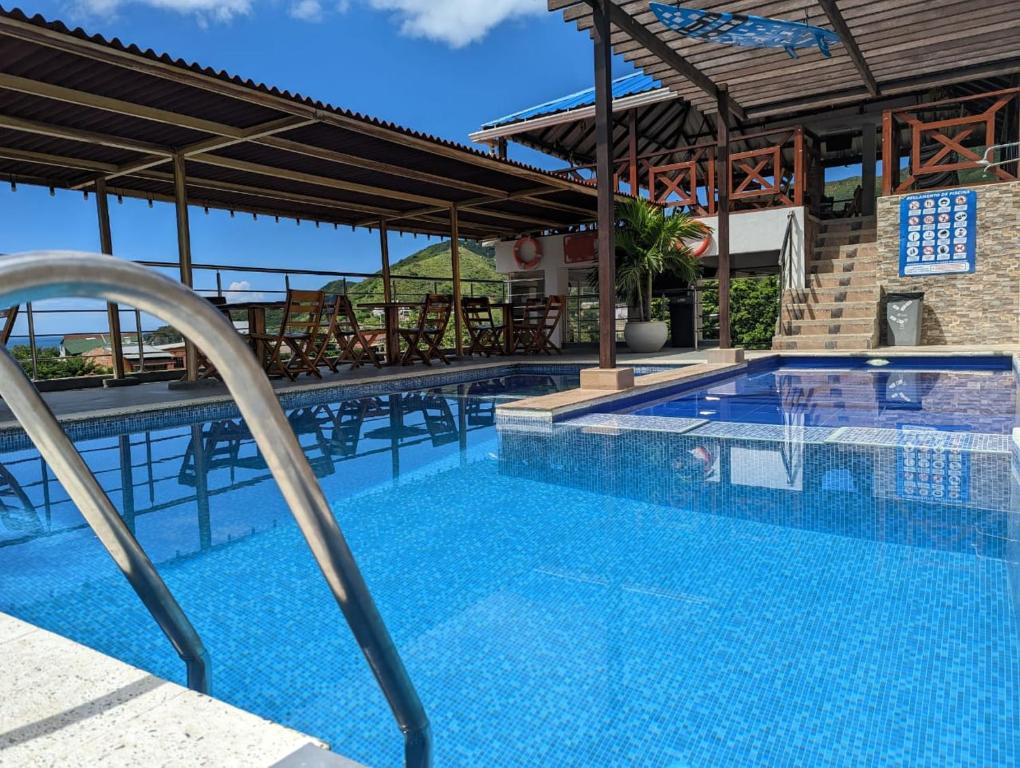 a large swimming pool with chairs and a building at Hostal Casa Roma in Taganga