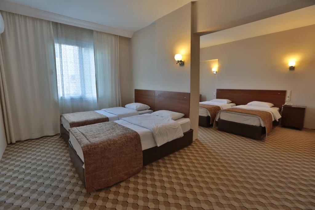 a hotel room with three beds and a mirror at Hosta Otel in Mersin