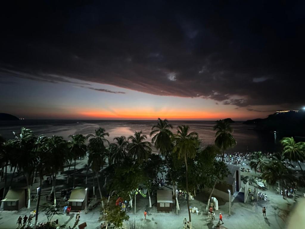 a view of a beach at sunset with palm trees at Vista increíble Chirama Rodadero in Santa Marta