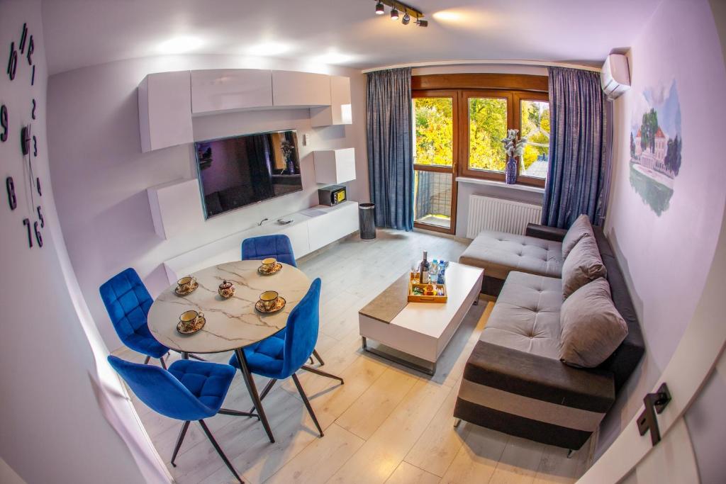 a kitchen and living room with a table and blue chairs at Apartament Książęcy przy Pałacu - klimatyzacja in Żagań