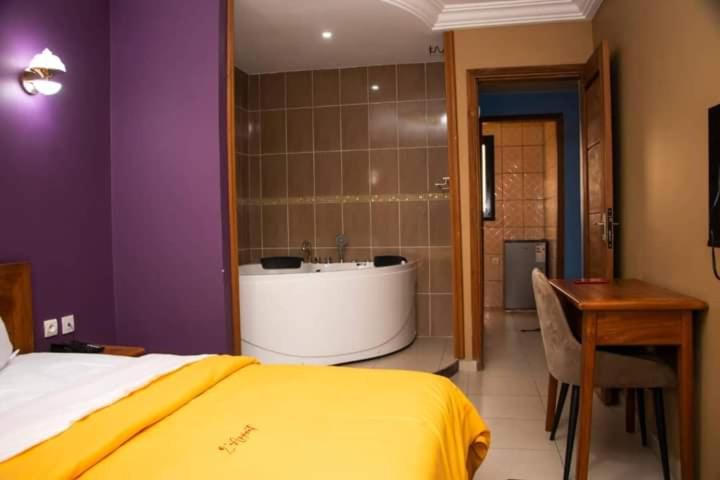 a bedroom with a tub and a bed and a desk at Résidence l'Appart in Yaoundé