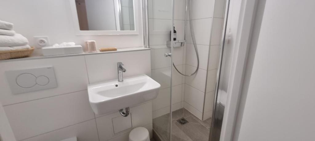 a white bathroom with a sink and a shower at Hotel De L'Europe in Perros-Guirec