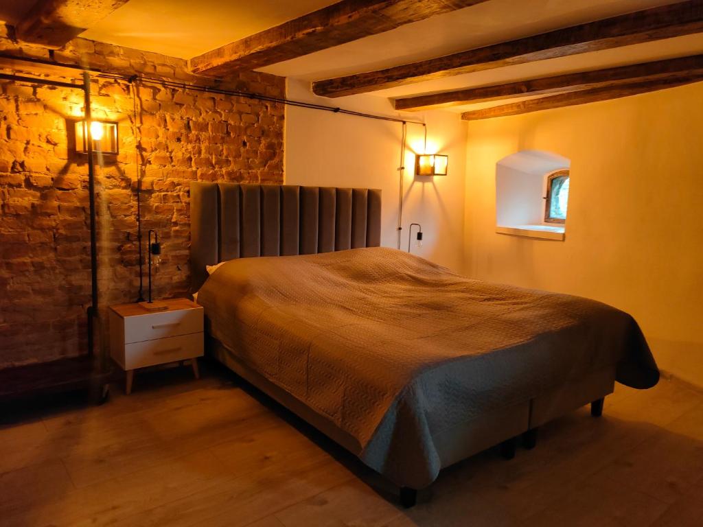グニェズノにあるWieża Gniezno Apartament WIEŻAのベッドとレンガの壁がある寝室