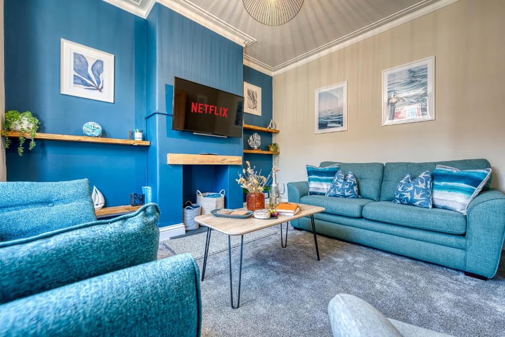 una sala de estar azul con 2 sofás azules y una mesa en Modern 2-Bed Stylish Contractor House, Prime Portsmouth Location & Parking - By Blue Puffin Stays, en Portsmouth