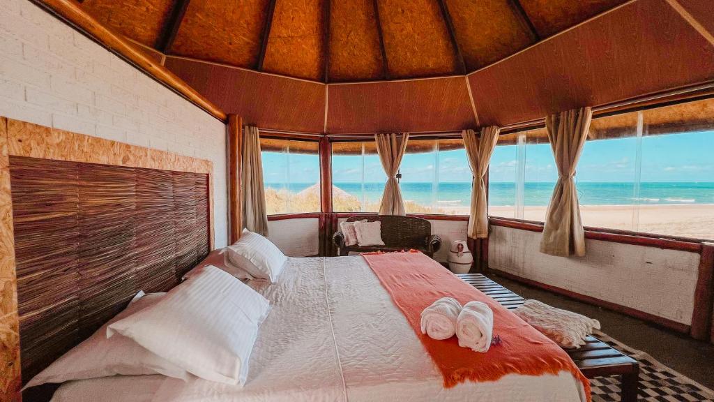 een slaapkamer met een bed en uitzicht op het strand bij Ocas do Índio Hotel Spa in Beberibe