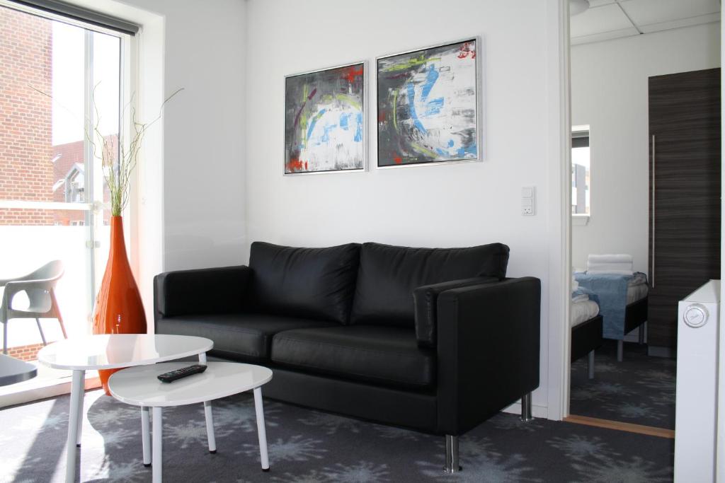 a living room with a black couch and a table at ApartHotel Faber in Aarhus