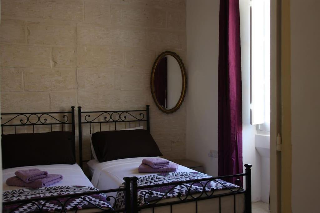 sypialnia z 2 łóżkami i fioletowymi ręcznikami w obiekcie Quaint Studio apartment w mieście Birgu