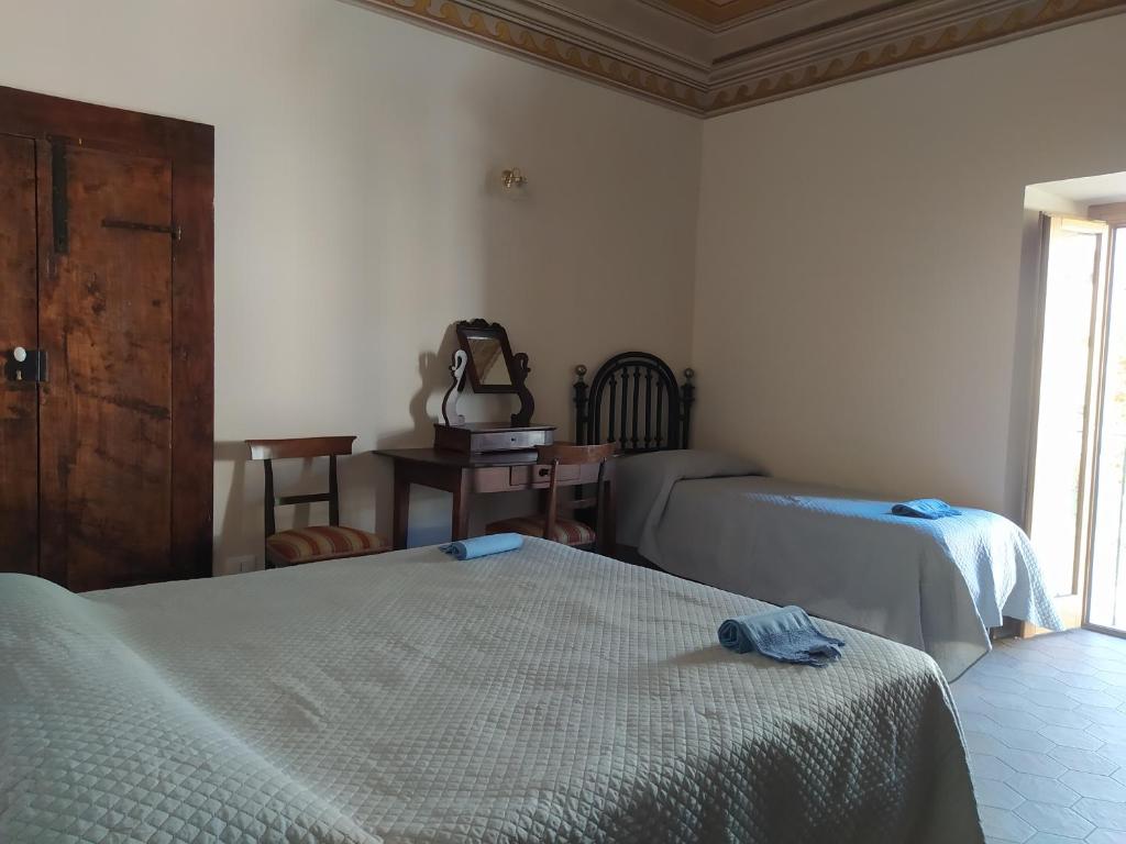 Camarda的住宿－Locanda di Posta，一间卧室设有两张床、一张桌子和一个窗口