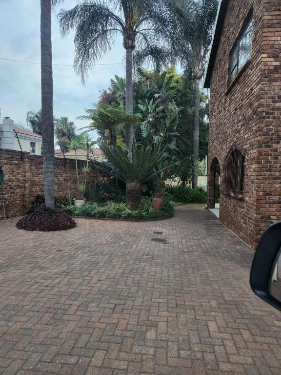 een stenen oprit met palmbomen en een gebouw bij Squirrels Guest House in Johannesburg