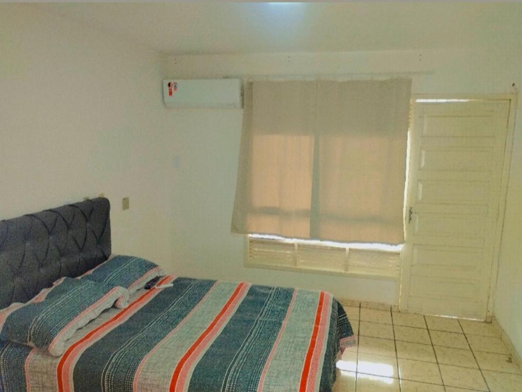 1 dormitorio con cama y ventana en Duplex Encantador en Guarapari