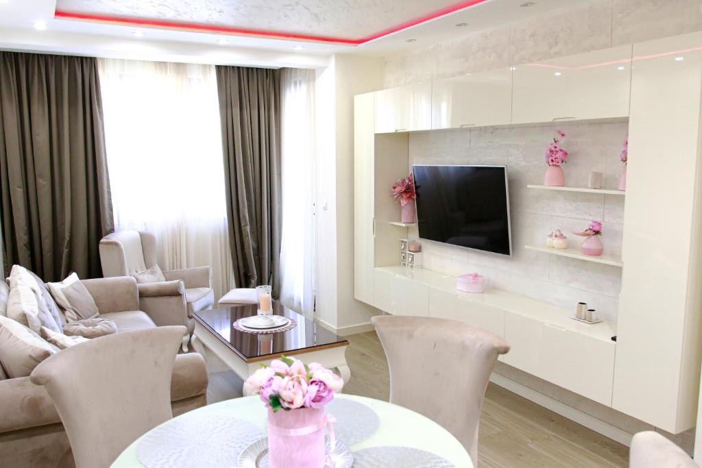 sala de estar con mesa, sillas y TV en Apartman Bajka, en Zlatibor