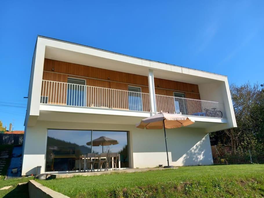 uma casa com uma varanda com mesas e guarda-sóis em Casa moderna julio y agosto em Ferrol