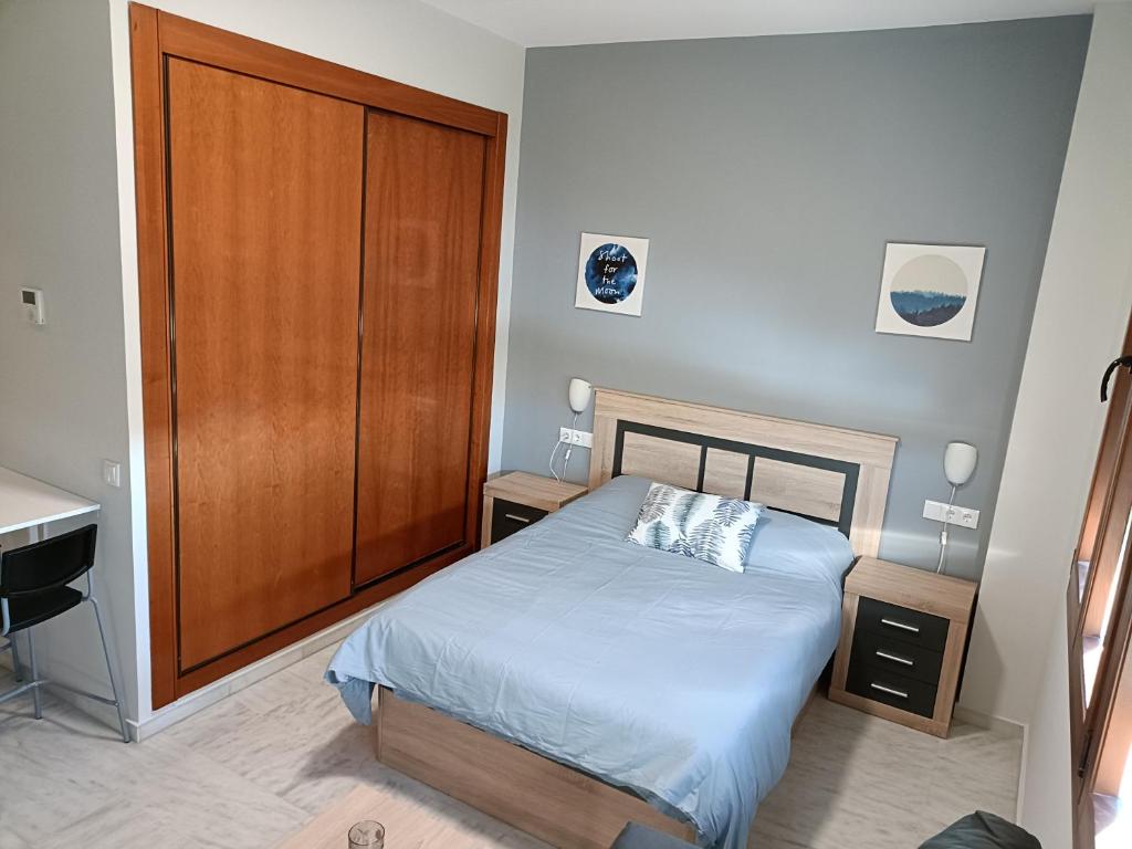 - une chambre avec un lit et une armoire en bois dans l'établissement Estudio Lux-Palacio de Congresos, à Séville