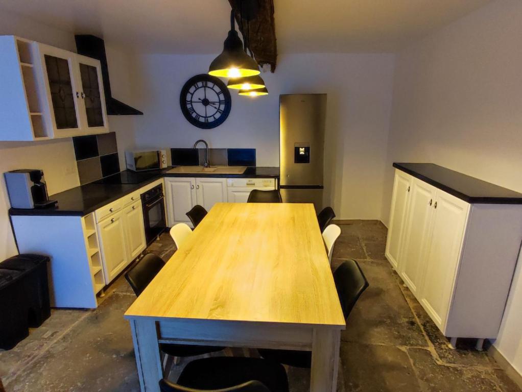 une cuisine avec une table en bois et une horloge au mur dans l'établissement La maison de vos vacances, à Marmeaux