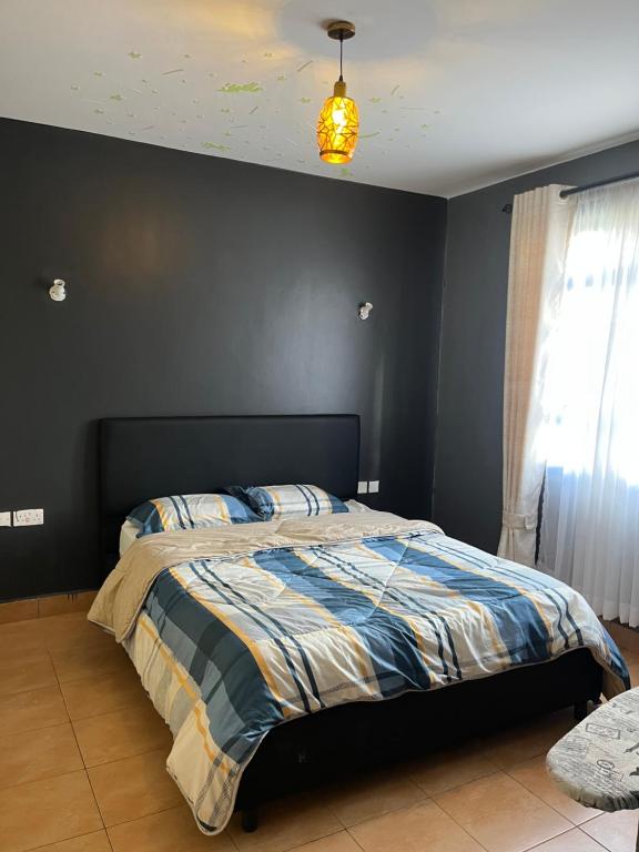 ein Schlafzimmer mit einem Bett und einer schwarzen Wand in der Unterkunft Family-Friendly Home in Nairobi