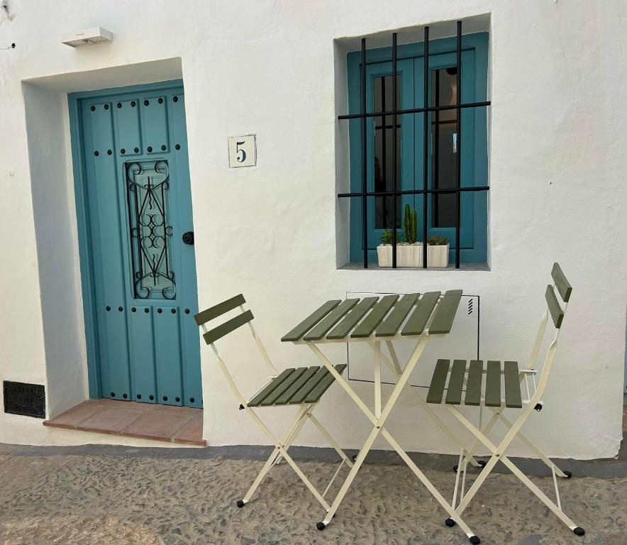 two chairs and a table in front of a door at CASA MÚA in Frigiliana