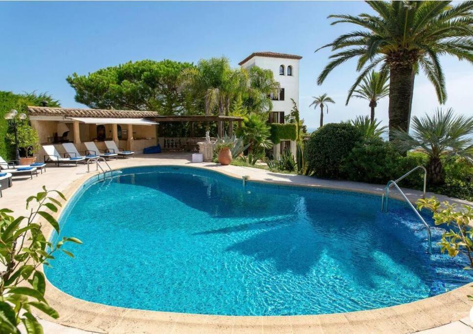 uma piscina em frente a uma casa com palmeiras em LE CASTEL ROSE Super Cannes, face aux Îles de Lérins em Vallauris