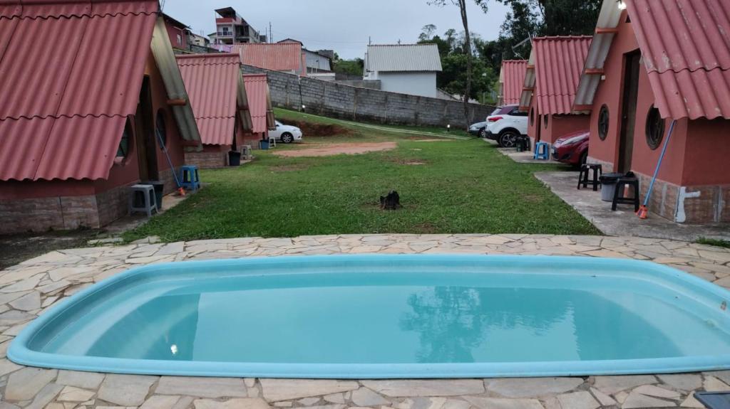 a blue swimming pool in a yard with houses at Chalézinhos São Roque in São Roque