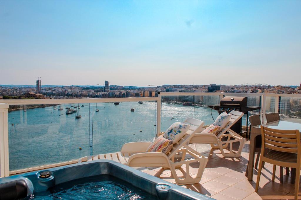 斯利馬的住宿－Exceptional Tigne Seafront Apartments by Shortletsmalta，阳台设有热水浴池、椅子和桌子