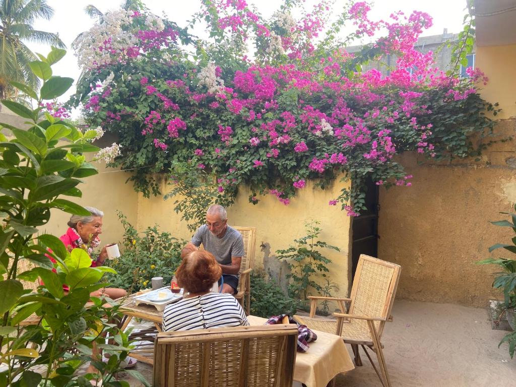 un groupe de personnes assises à une table dans un jardin fleuri dans l'établissement Le Poulagou, à Saint-Louis