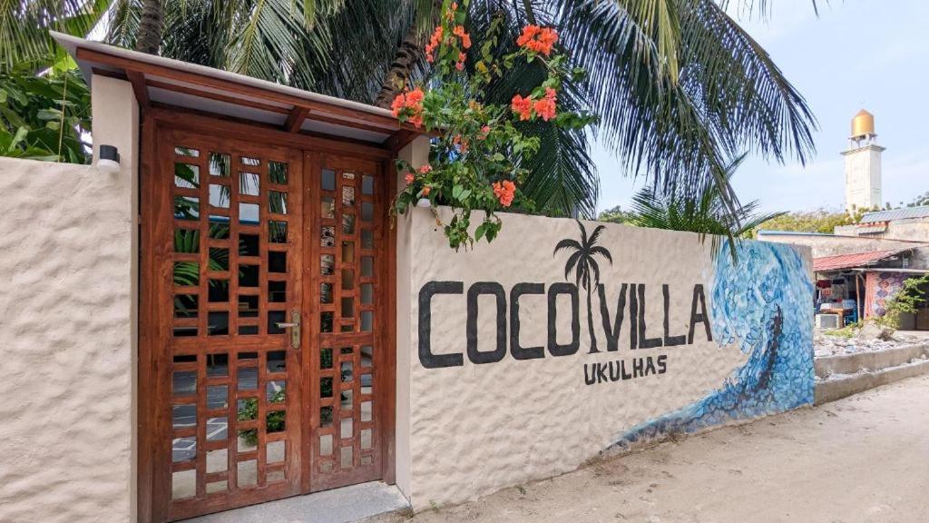 una pared con una puerta de madera con un cartel en Coco Villa Ukulhas, en Ukulhas