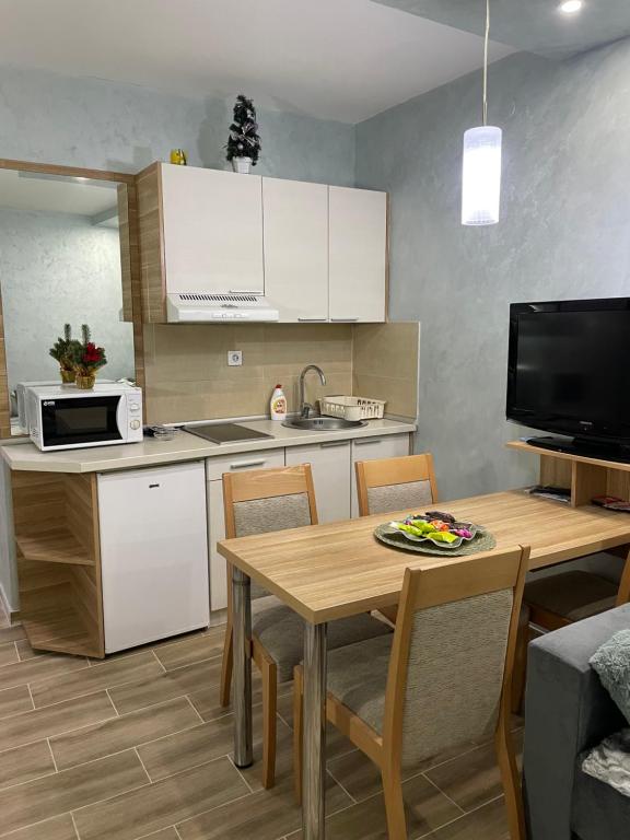 eine Küche mit einem Tisch und eine Küche mit weißen Schränken in der Unterkunft Apartmani Dušica Konaci Kopaonik in Kopaonik