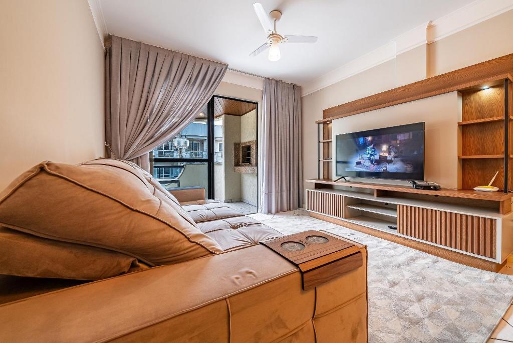 sala de estar con sofá y TV de pantalla plana en 299 - Excelente apto com 03 dormitórios, a 100m da praia de Bombas, en Bombinhas