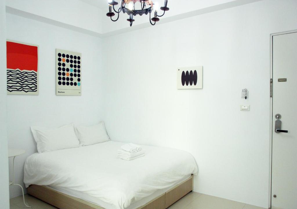 a white bedroom with a bed and a chandelier at 夕映安平 in Tainan
