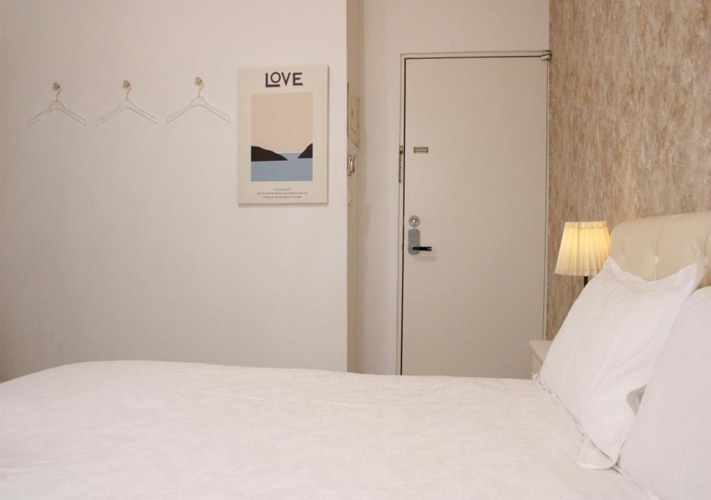 a bedroom with a white bed and a door at 夕映安平 in Tainan