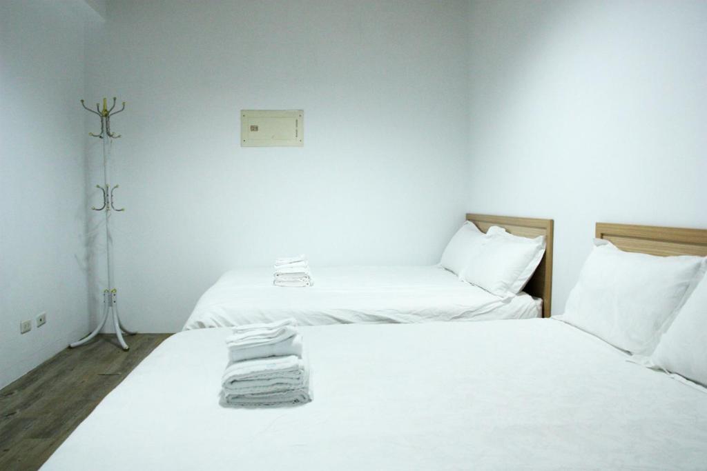 two beds in a room with white sheets and pillows at 夕映安平 in Tainan