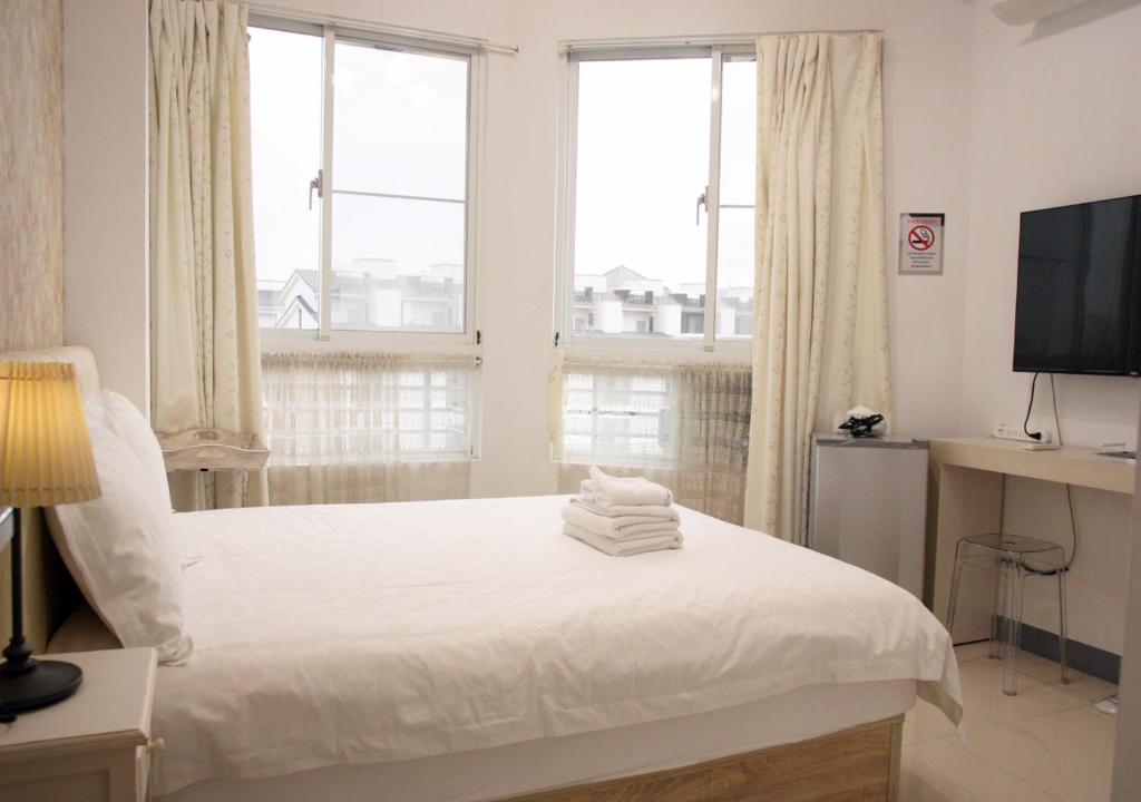 a white bedroom with a bed and a television at 夕映安平 in Tainan
