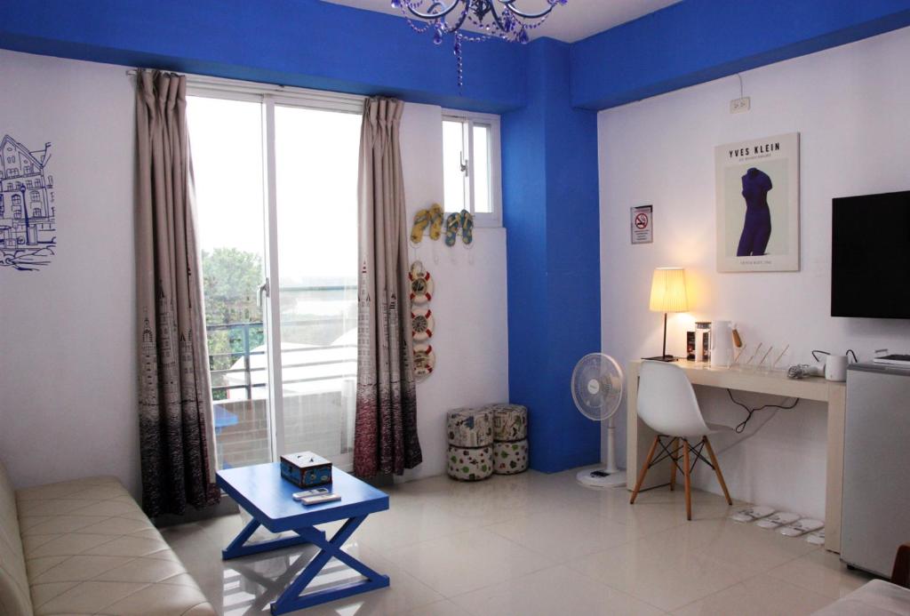 a living room with blue walls and a table and a desk at 夕映安平 in Tainan