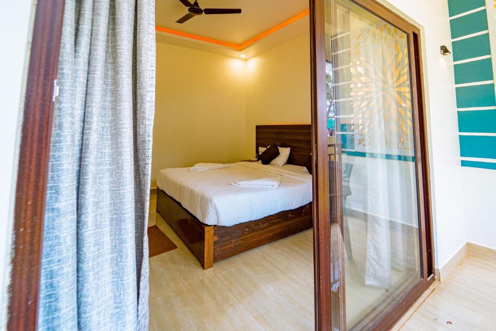 a small bedroom with a bed and a mirror at Darsy Residency in Agonda